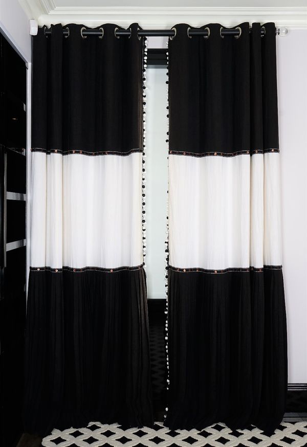 A pair of graphic black and white linen curtains, the lower panels with dress maker's pleats, edged with black and white ball tassels. 190cm wide x 30