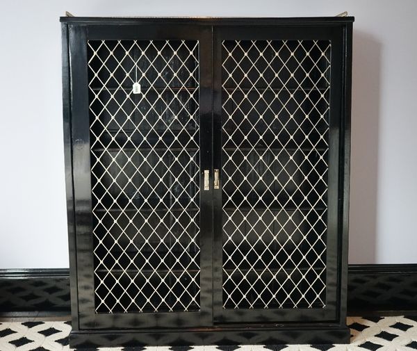 An ebonised bookcase, with silvered gallery and enclosed by a pair of sliding grille doors, 127cm wide x 154cm high.