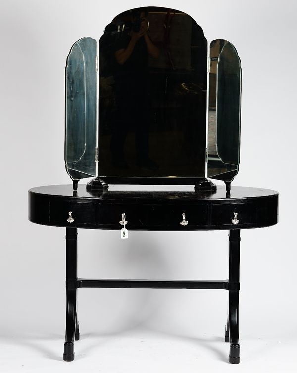 An ebonised oval dressing table, with triptych mirrors and three frieze drawers, on splayed end standards, 122cm wide x 169cm high.