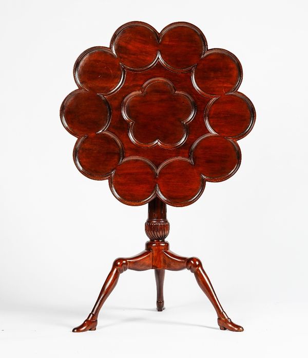 A reproduction mahogany Isle of Man supper table, with dished circular tilt-top and fluted column, the tripod base formed as 'legs' terminating in 'sh