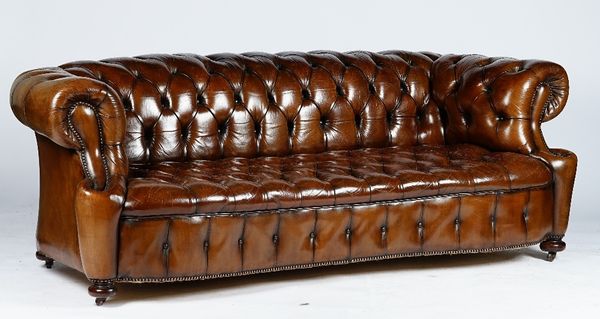 A Victorian style Chesterfield settee, button upholstered in brown leather with close nailed arms, on bun feet and castors, 224cm wide x 72cm high.