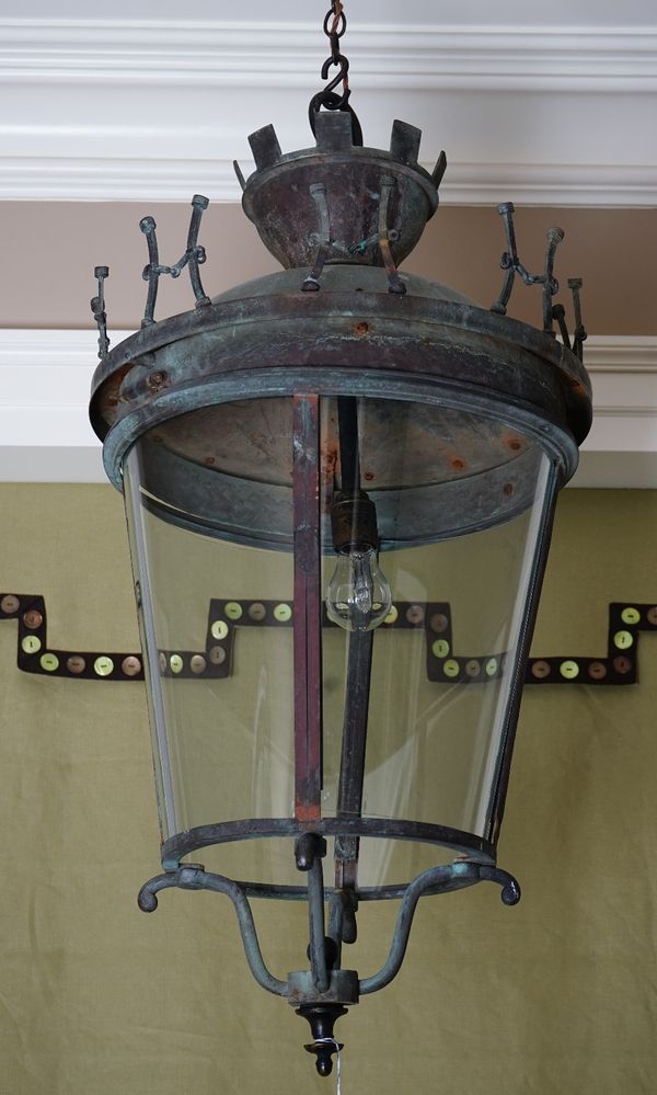 A wrought metal porch lantern, in 18th century style, with curved glass sides, surmounted by a gallery modelled as horse hames.43cm diameter x 98cm hi