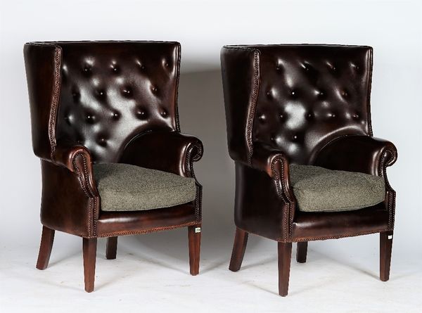 A pair of reproduction George III style armchairs with curved button-down upholstered leather backs and sides, and loose seat cushions, 81cm wide x 11