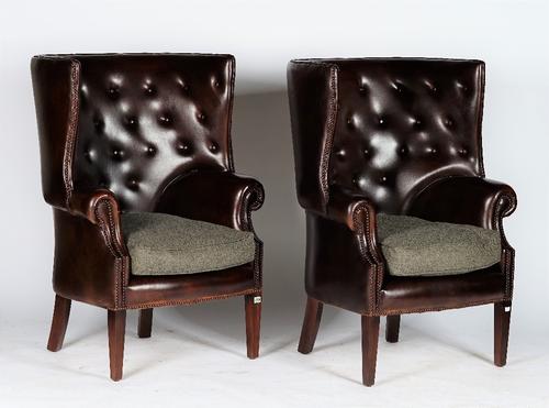 A pair of reproduction George III style armchairs with curved button-down upholstered leather backs and sides, and loose seat cushions, 81cm wide x 11