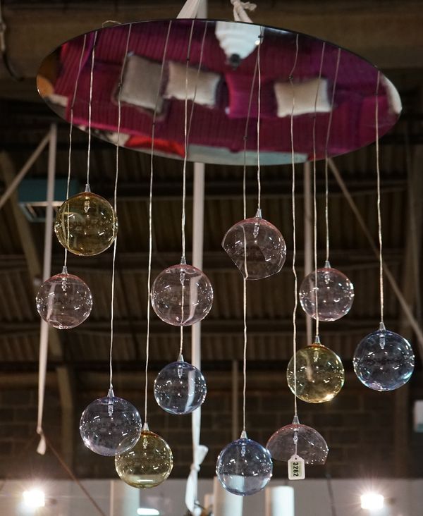 A contemporary light fitting, hung with twelve coloured glass balloons, suspended from a circular mirror.