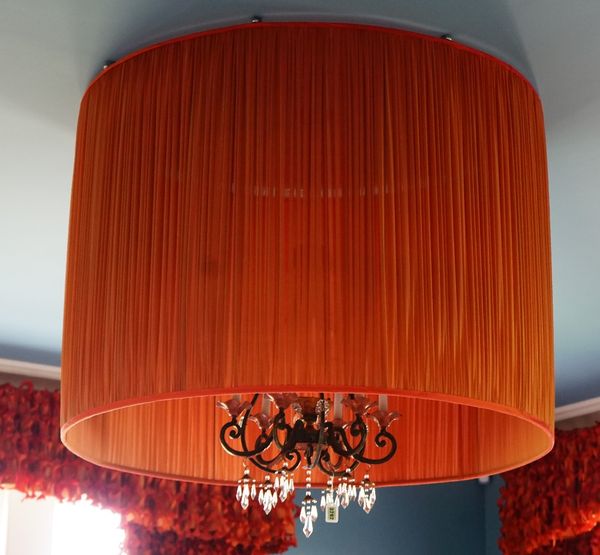 A wrought metal six light chandelier, of scrolling form, hung with faceted glass drops in an orange oversized pleated shade (2), 65cm high