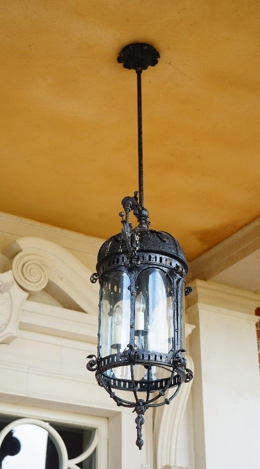 A wrought metal hanging lantern, in 18th century style, of four lights, with glass panels and foliate scroll surmount, 130cm wide x 82cm high