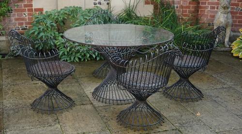A wrought metal wirework five piece loggia suite, four chairs with scroll over backs, the circular table with plate glass top (5).
