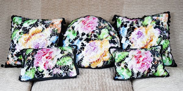 Two pairs of black silk and cut-velvet cushions, with multi-coloured floral designs and a matching circular cushion (5).