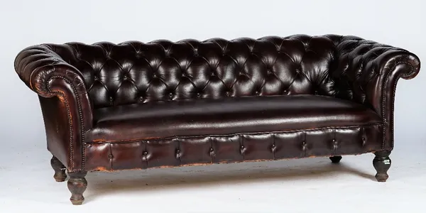 A Victorian style Chesterfield settee, button upholstered in brown leather with close nailed arms, on bun feet and castors, 207cm wide x 70cm high.