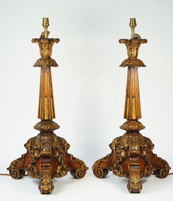 A pair of Continental walnut carved table lamps of rococo style, early 20th century, with gilt traces over a fluted hexagonal column and scroll work t