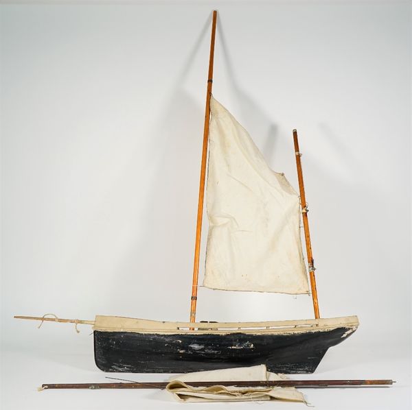 A small pond yacht, English, 20th century with single main mast, linen sails and black/white painted wooden hull, 64cm wide.