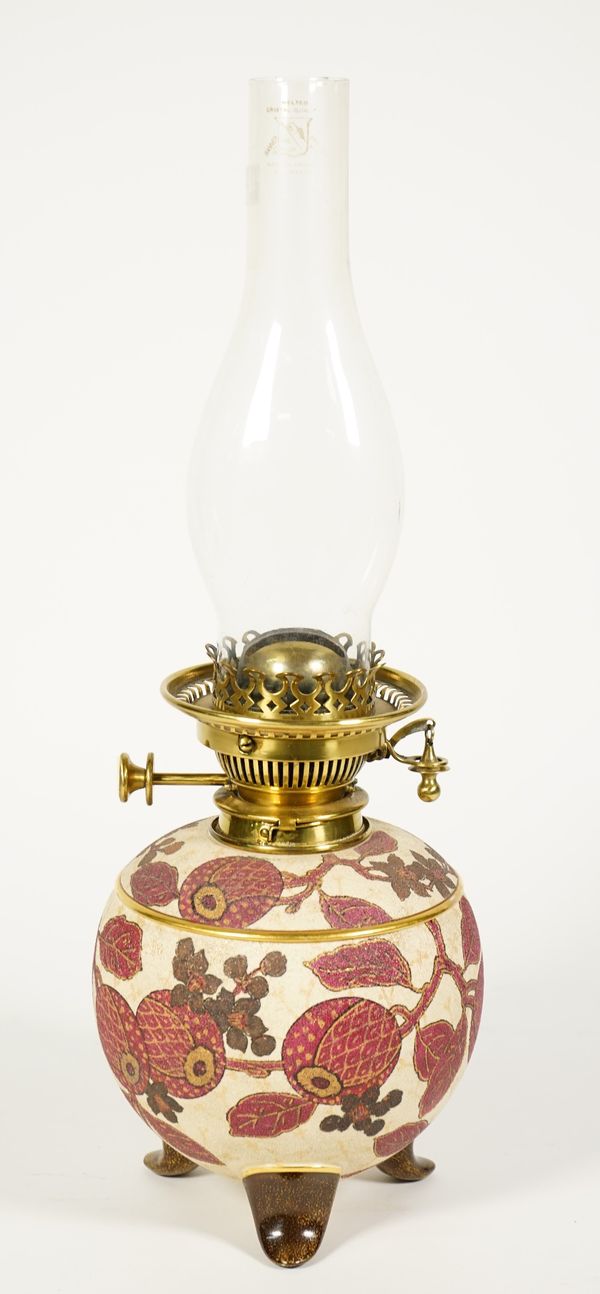 A Minks No 2 pottery oil lamp c. 1886, the circular foliate painted body raised on three shaped feet with brass hinks burner and glass flue, 48cm high