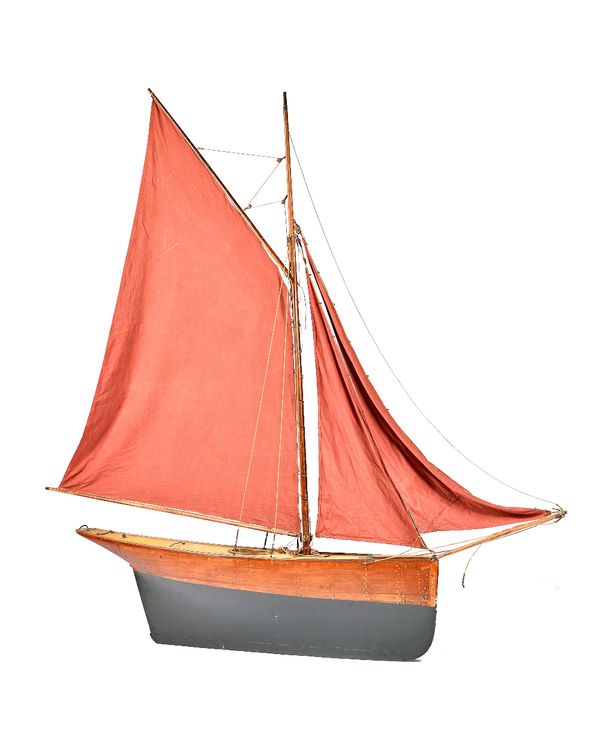 A large pond yacht, English, late 19th century , the gaff rigged model with single mast and dark red sails, pinned and planked wooden hull, 166cm wide