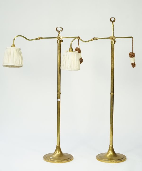 A pair of Victorian style brass adjustable floor lamps, modern with angle poise arms, circular spreading foot and cream pleated shades, (2).