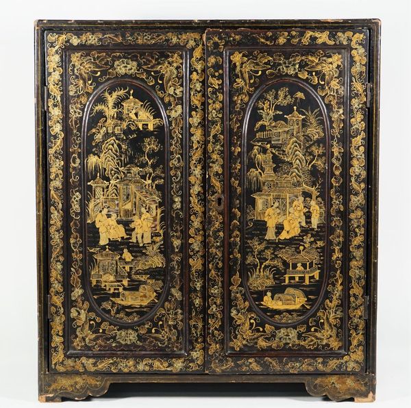 A Japanese table cabinet, circa 1900, chinoiserie decorated against an ebonised rectangular body, the full height hinged doors opening to reveal an ar