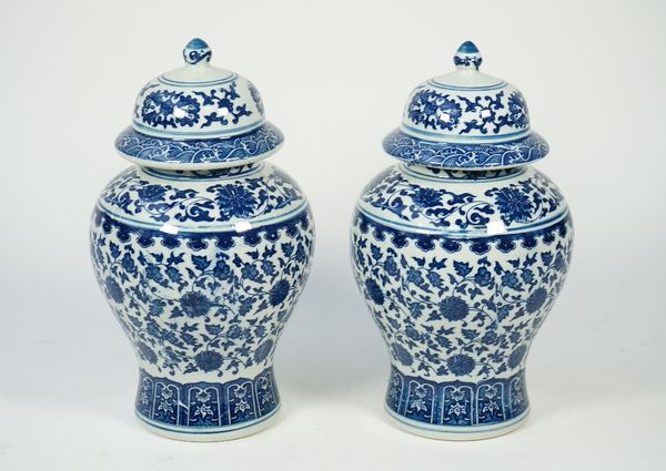 A pair of modern Chinese style blue and white porcelain vases and covers, each foliate decorated against a waisted ground, printed mark to base, 30cm