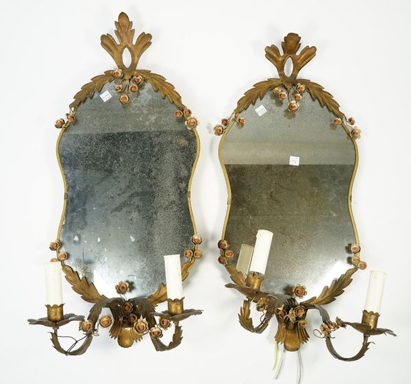 A pair of Victorian style shaped glass wall mirrors, early 20th century, each with a two light wall sconce and sheet brass foliate decoration, 62cm hi