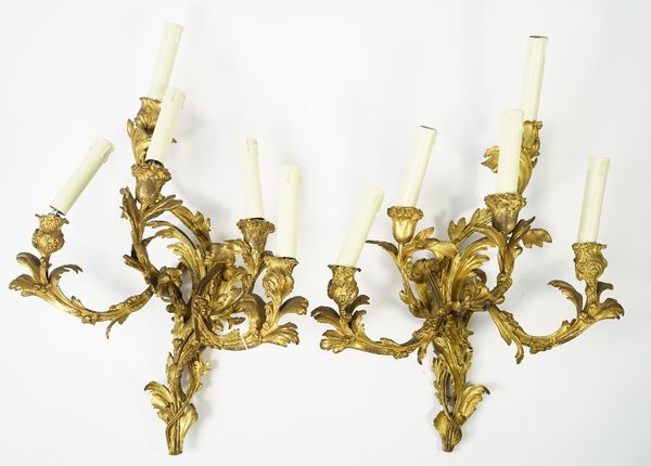 A pair of gilt bronze rococo style five branch wall appliques, 19th century, each with foliate cast decoration, 53cm high, (2).