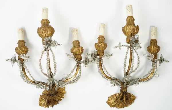 A pair of Louis XVI style giltwood and wrought iron three branch wall appliques, hung with glass drops with a matching wooden back plate, 35cm high, (