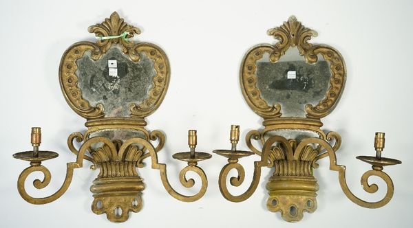 A pair of gilt metal two branch wall sconces, late 19th century, each with a shaped mirror backplate issuing two scroll arms, back plate 48cm high, (2