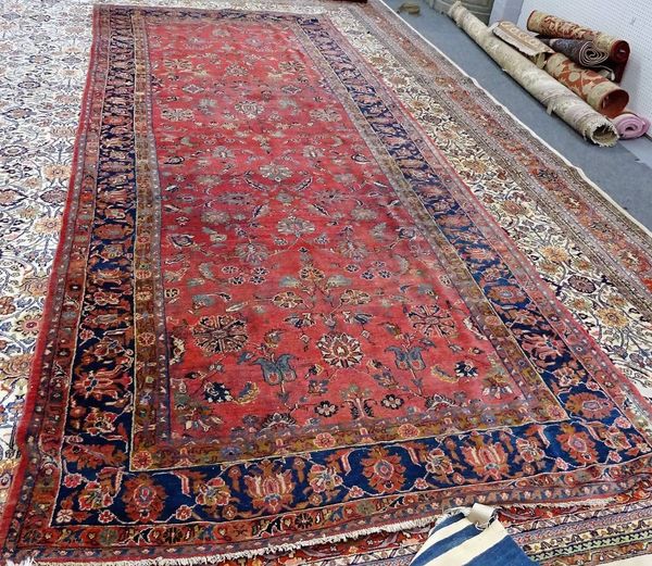 A Malayer Kelleh carpet, Persian, the pink field with palmettes and floral leaf sprays; an indigo palmette and floral vine border, 493cm x 210cm.