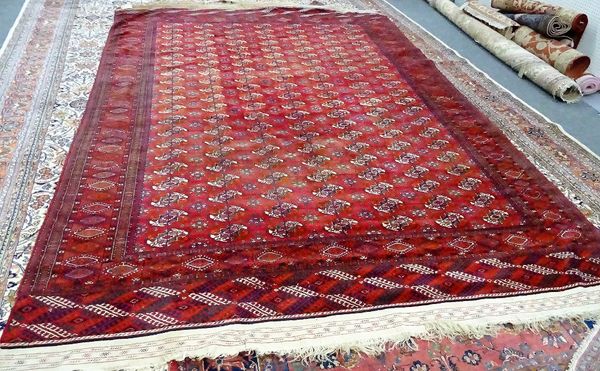 A Tekke Turkman carpet, the madder field with seven columns of twenty one guls supporting crosses, a sunburst border, flat weave ends, 480cm x 290cm.