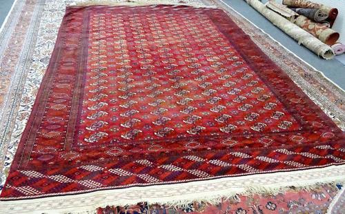 A Tekke Turkman carpet, the madder field with seven columns of twenty one guls supporting crosses, a sunburst border, flat weave ends, 480cm x 290cm.