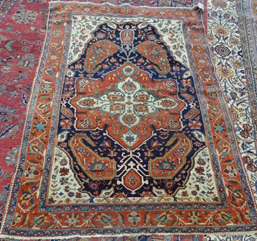 A Fereghan rug, Persian, the dark indigo field with a bold madder medallion with large boteh ends, ivory spandrels, with floral sprays, a madder roset