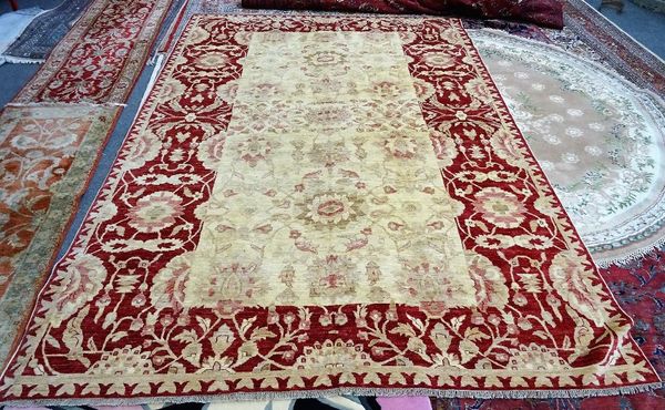 A Turkish carpet, the pale fawn field with a faded palmette and floral vine design; a wide madder palmette and vine border, 368cm x 250cm.