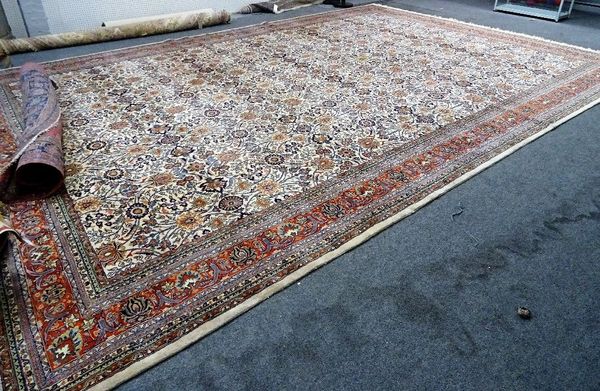 A Kashan carpet, Persian, the ivory field with an allover rosette, palmettte and trailing floral vine design; a madder palmette and lily border, 596cm