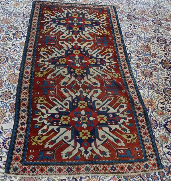 A Chelaberd Kazak Caucasian carpet, the madder field with three bold ivory medallions, an ivory star border, 250cm x 123cm.