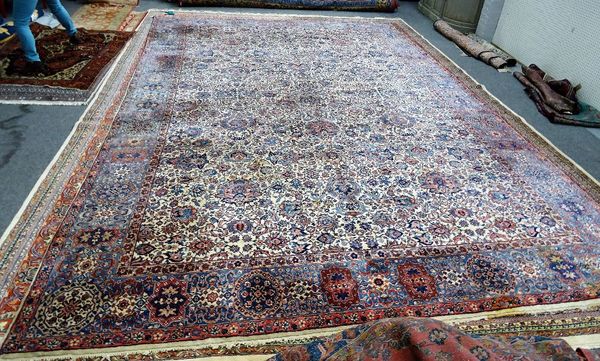 An Esfahan carpet, the ivory field with an allover palmette and floral spray design, pale indigo border, with large roundels and ribbons, 550cm x 360c