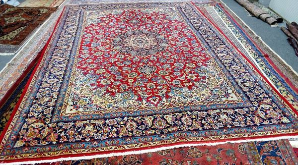 An Esfahan carpet, Persian, the madder field with an ivory and indigo sunburst medallion, ivory spandrels, all with abundant floral palmette vine and