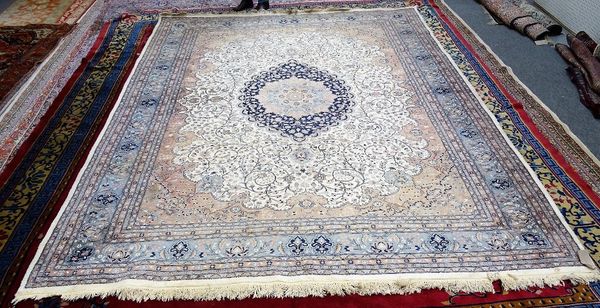 A Kashan part silk carpet, Persian, the ivory field with an indigo lobed medallion, madder sprandrels, all intricate floral vines, grey palmette borde