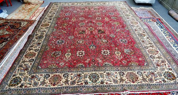 A Tabriz carpet, Persian, the madder field with an allover flower, vine and palmette design; an ivory complementary border, 423cm x 320cm.