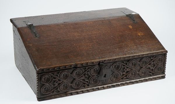 A 17th century oak bible box, the sloped front enclosing a three drawer interior over carved front panel, 64cm wide x 24cm high.