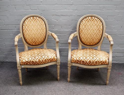 A pair of grey painted Louis XVI style open armchairs with serpentine seats on fluted supports, 57cm wide x 87cm high.