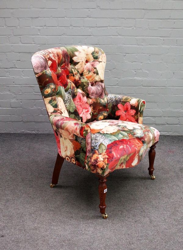 A Victorian style button back armchair with floral upholstery on turned supports, 70cm wide x 98cm high.