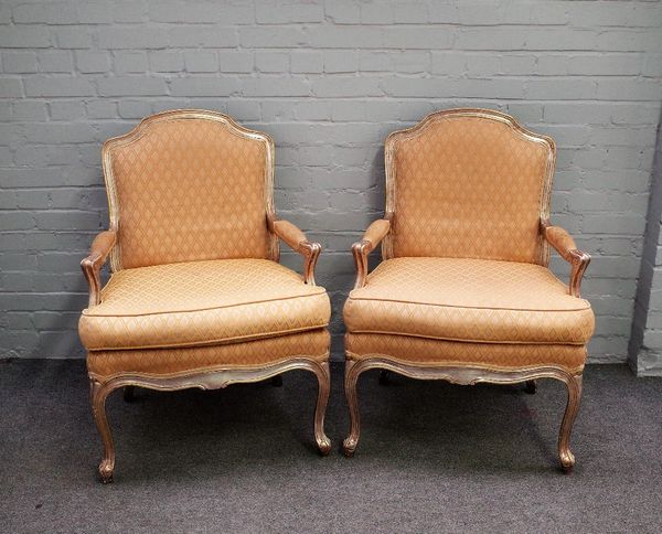 A pair of 18th century style silver framed open armchairs with serpentine seats, on scroll supports, 70cm wide x 96cm high.