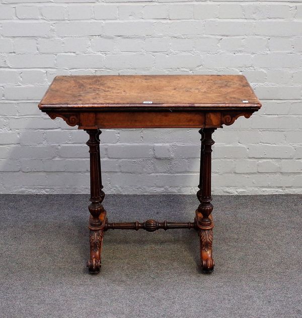 A Victorian figured walnut games table, with fold-out rectangular top on fluted columns and four scroll supports, 82cm wide x 72cm high.