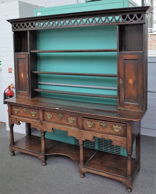 An 18th century oak dresser, the open three tier plate rack with pair of cupboards over a three drawer base united by pot board undertier, 194cm wide