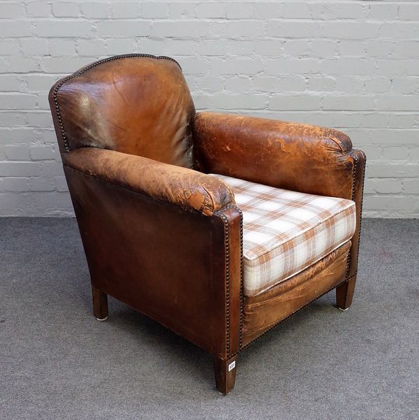 An early 20th century studded brown leather upholstered easy armchair on tapering block supports, 75cm wide x 86cm high.