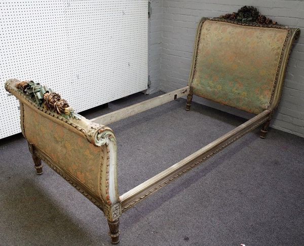 An early 20th century North European polychrome painted scroll end single bed, deeply relief carved with ribbon tied floral sprays, 115cm wide, the he