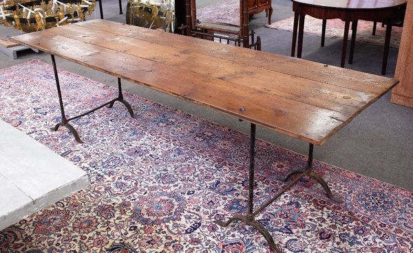 A pine kitchen table, the triple plank top on a pair of wrought iron trestle supports, 82cm wide x 254cm long.