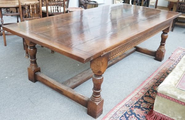 A 17th century style oak refectory table, the cleated plank top on turned supports, united by 'H' stretcher, 121cm wide x 259cm long.