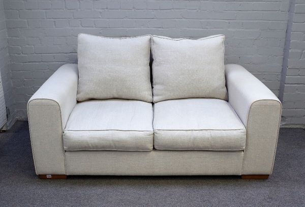 Heals; a Moretta small seat sofa upholstered in cream fabric on block feet, 163cm wide x 75cm high.