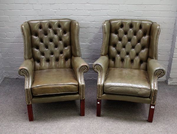 A pair of George II style brass studded green leather upholstered wingback armchairs on block supports, 80cm wide x 98cm high.