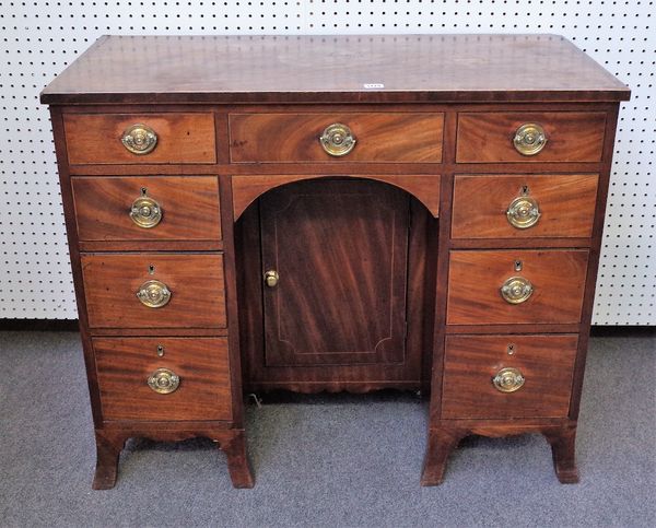 A late George III mahogany kneehole writing desk, with eight true and one dummy drawer about the cupboard, on splayed bracket feet, 97cm wide x 81cm h