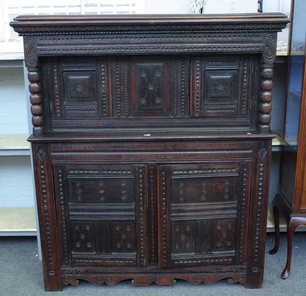 A 17th century and later oak court cupboard with raised double panel doors, flanked by bobbin turned columns, over a pair of triple panel lower doors